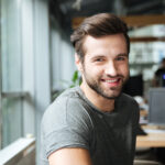 handsome smiling young man sitting in office coworking.